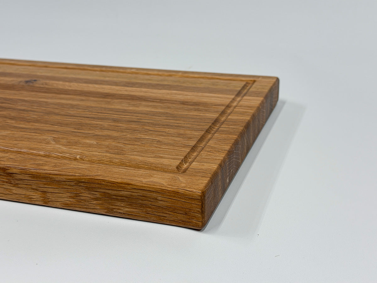 Corner detail of a handcrafted white oak cutting board showing the juice groove.