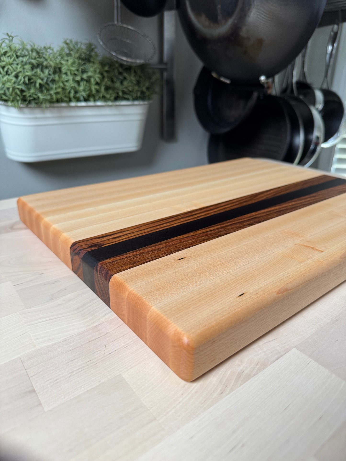 Angled view of the Cottingham edge grain cutting board in maple, walnut and zebrawood.