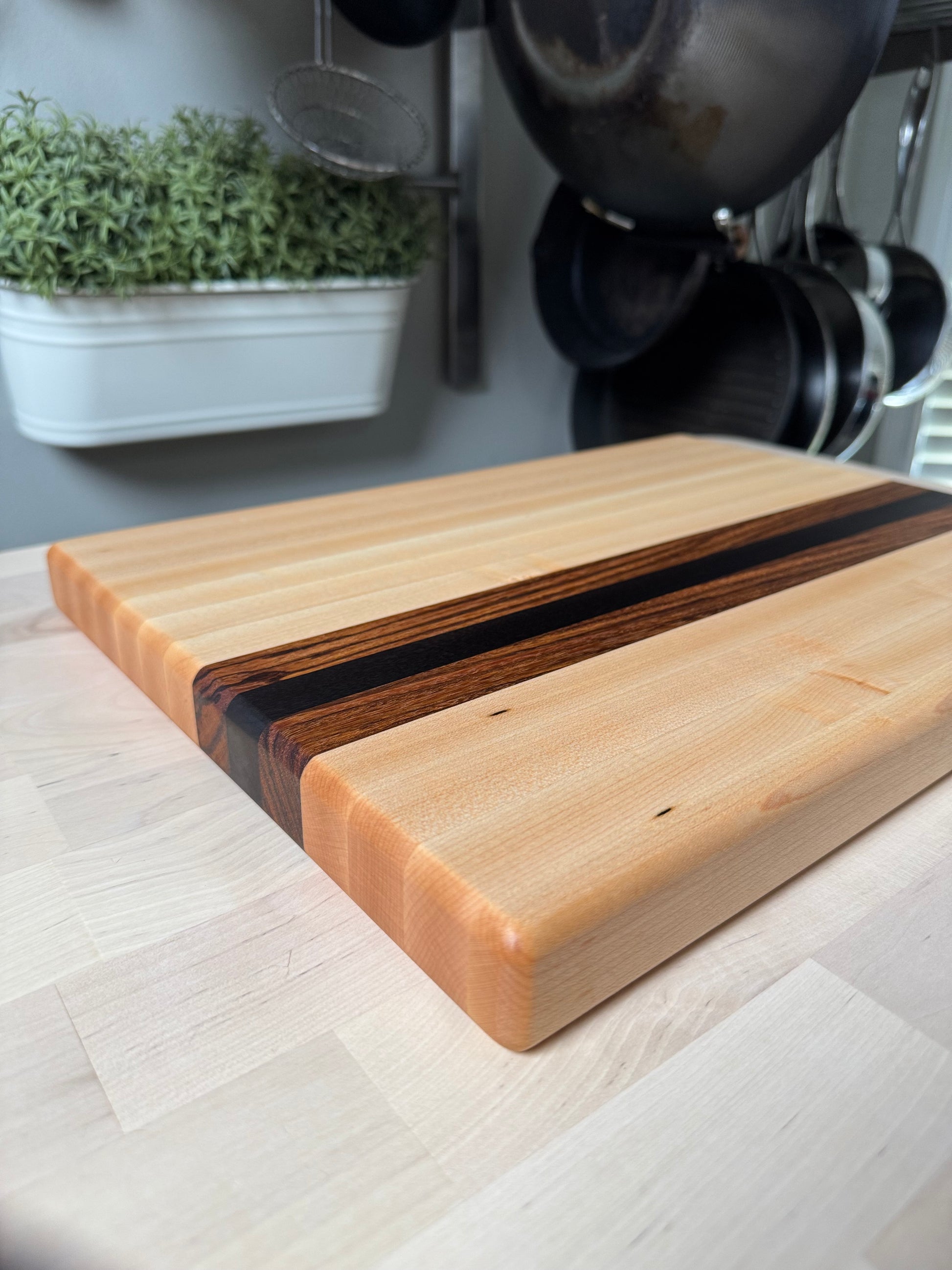 Angled view of the Cottingham edge grain cutting board in maple, walnut and zebrawood.