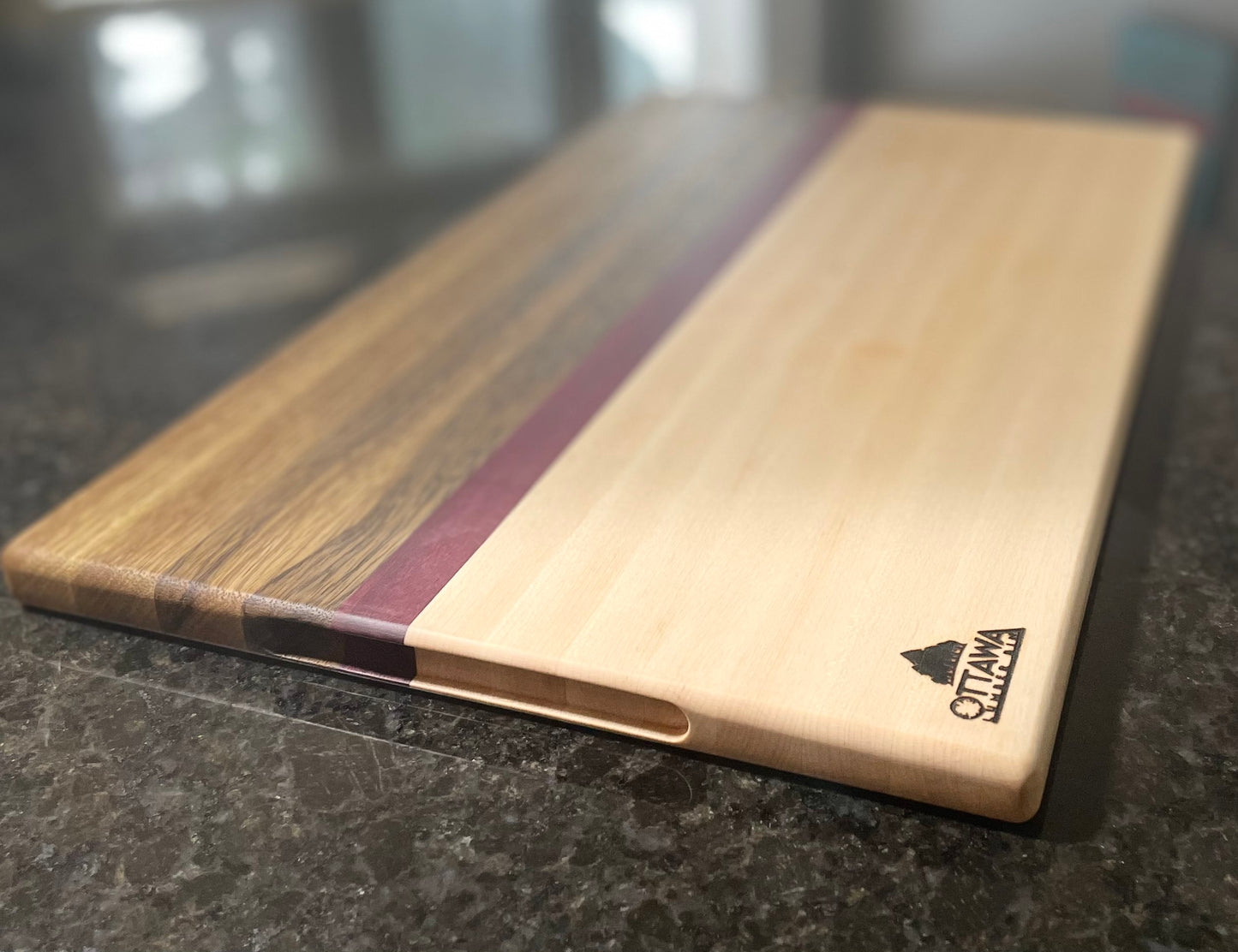 Top view of an edge grain charcuterie board featuring maple, black limba and Purpleheart accents.