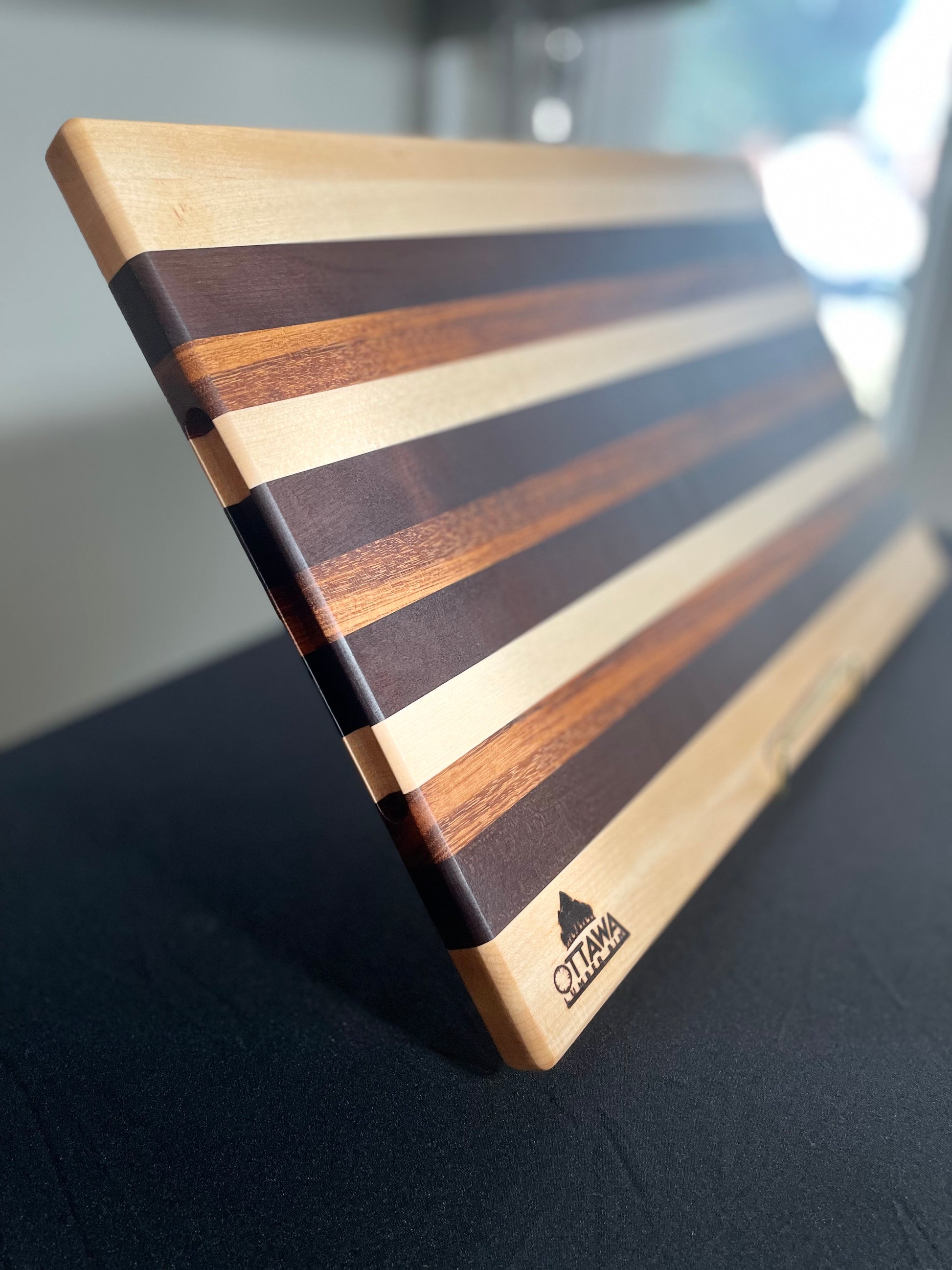 Close-up of a handcrafted edge grain charcuterie board highlighting the maple, walnut and tigerwood grain.