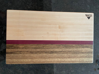 Close-up of a handcrafted edge grain charcuterie board showcasing maple, black limba and Purpleheart.
