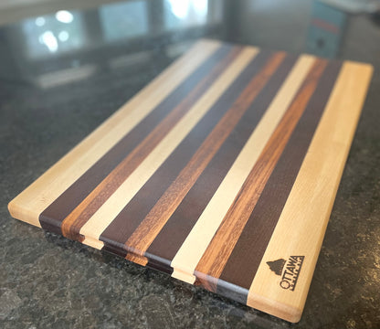 Top view of an edge grain charcuterie board featuring maple, walnut and tigerwood stripes.