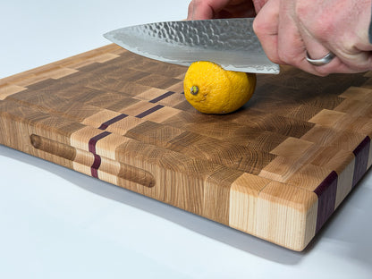 Chef slicing a lemon on a handcrafted end grain cutting board made from maple, white oak and Purpleheart.