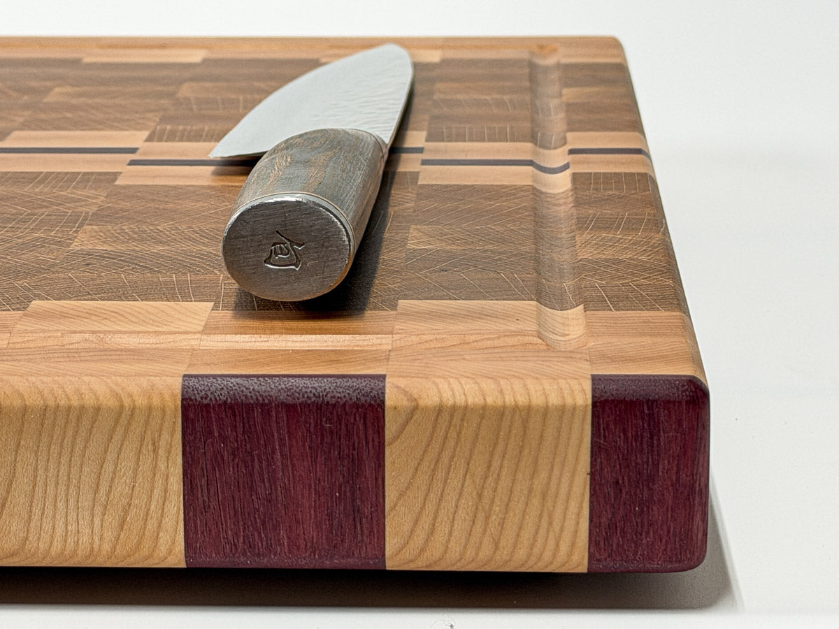 Side profile of a handcrafted end grain cutting board highlighting the maple, white oak and Purpleheart construction.