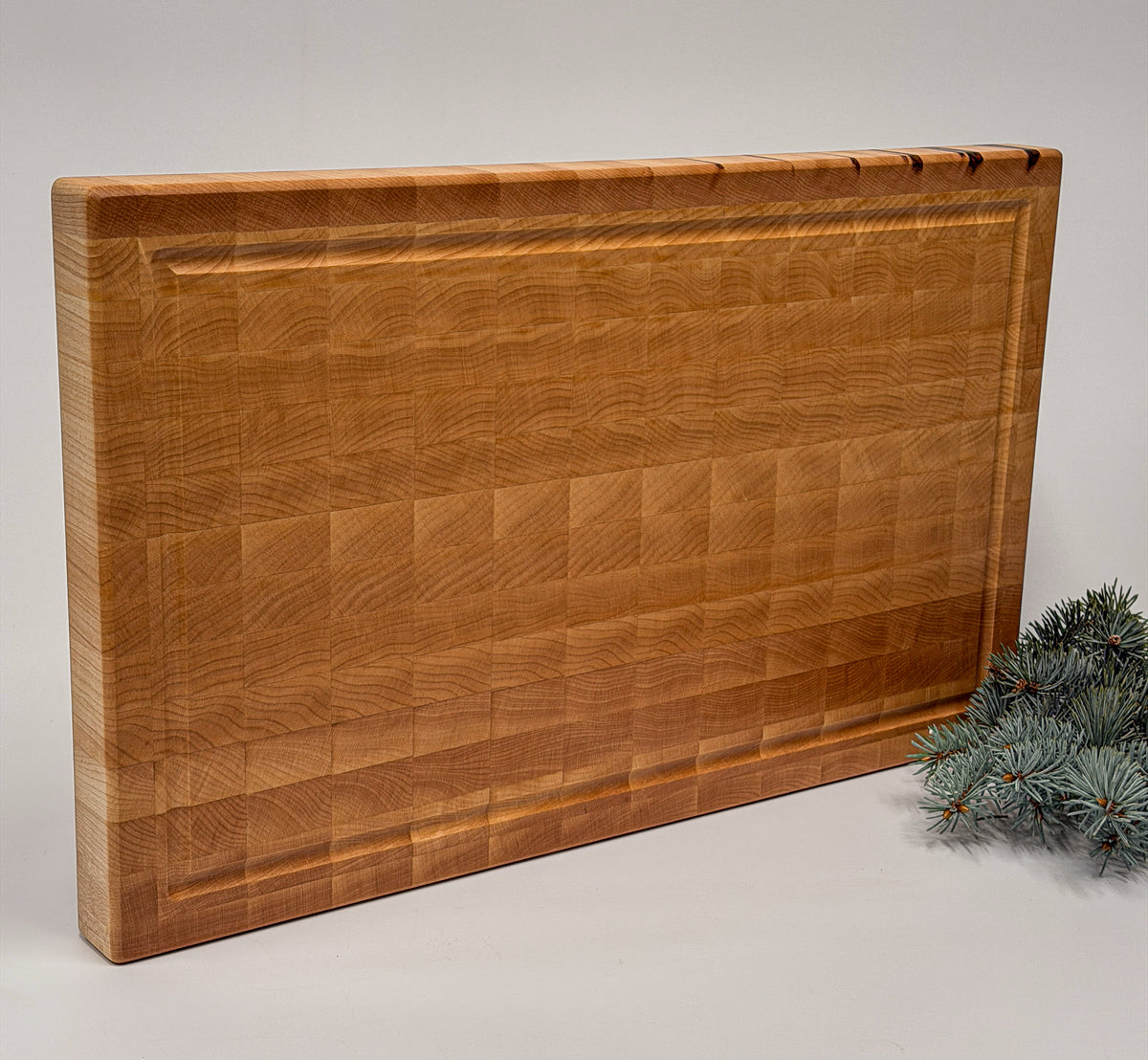 End-grain maple cutting board displayed with a small evergreen sprig for Christmas.