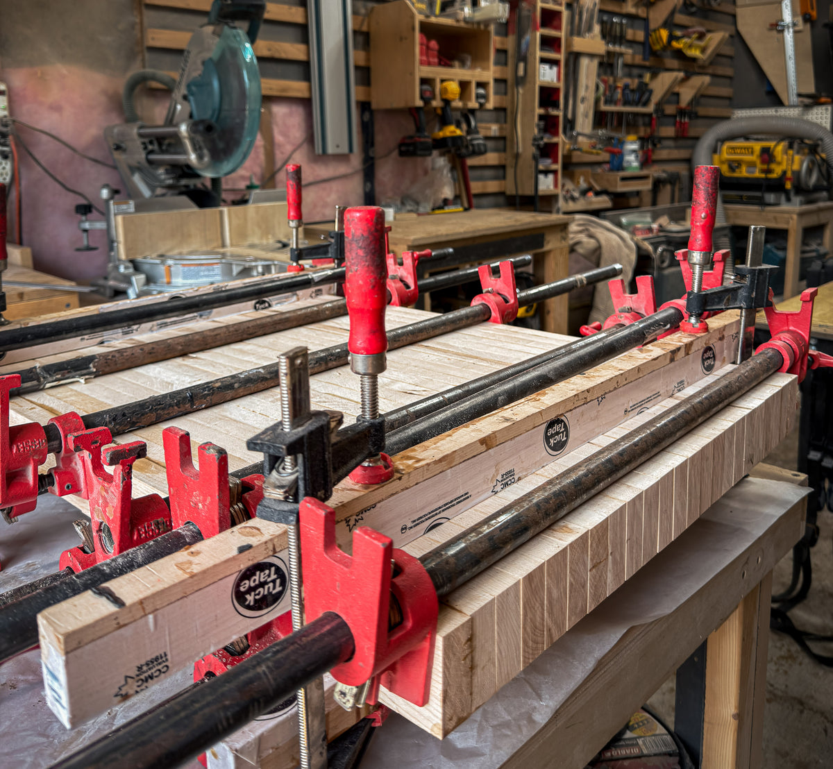 Maple cutting board glue-up secured with pipe clamps in the Ottawa Lumber Bin workshop.