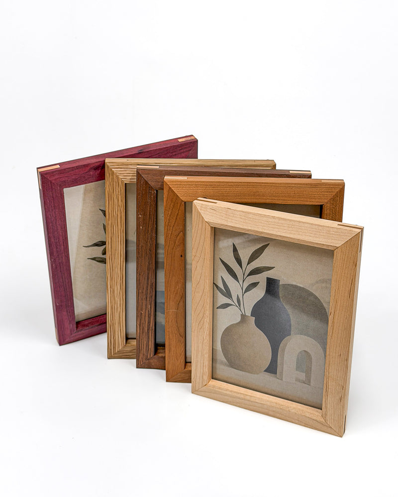 Five handmade picture frames in purpleheart, white oak, walnut, cherry and maple arranged on a white background.