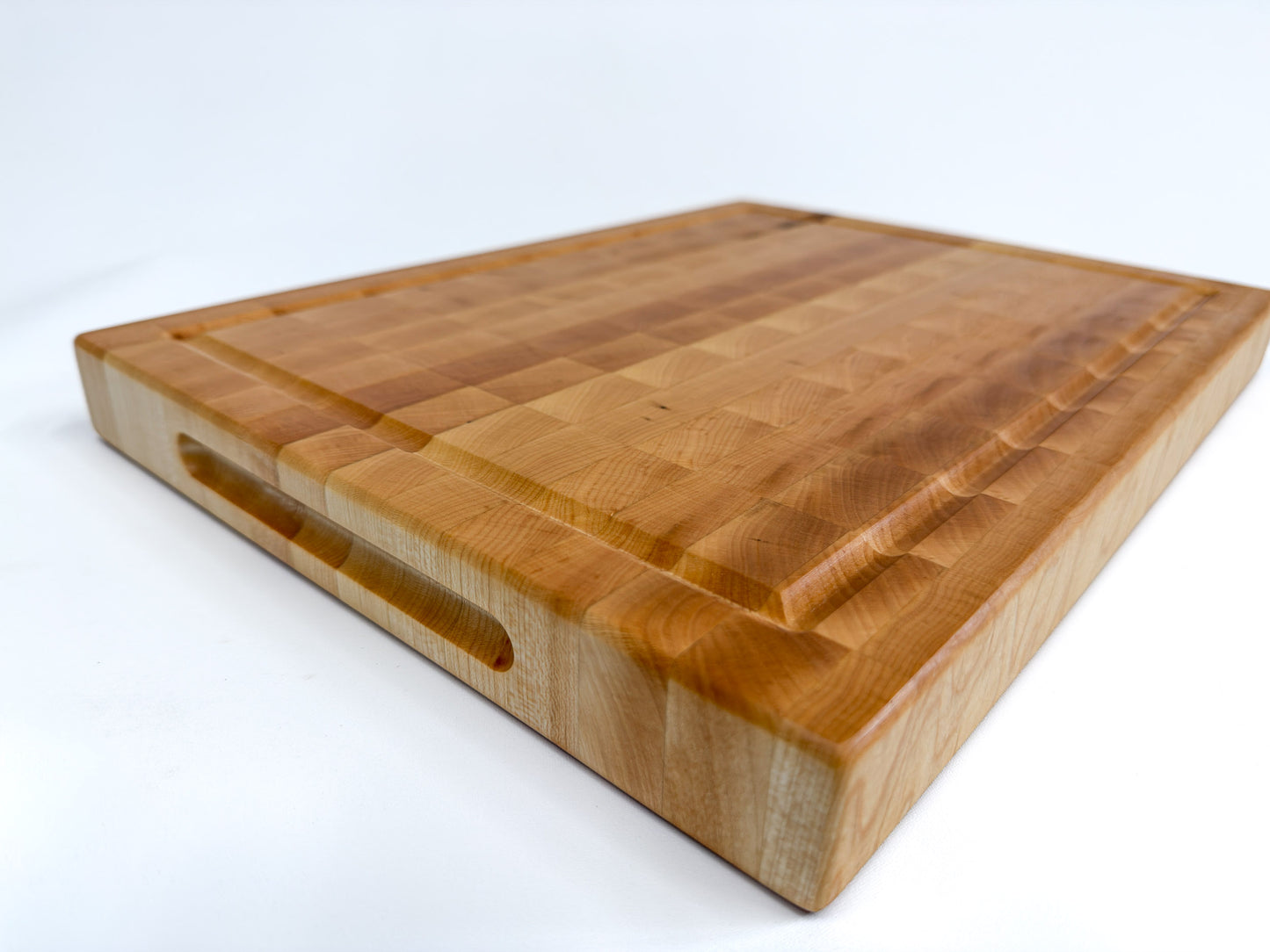 Close-up of the Langford maple end grain cutting board showing its recessed handle, juice groove and thick edge