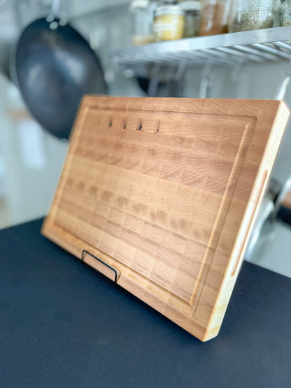 Angled view of a handcrafted maple end grain cutting board showing its thickness, edge profile, and juice groove.