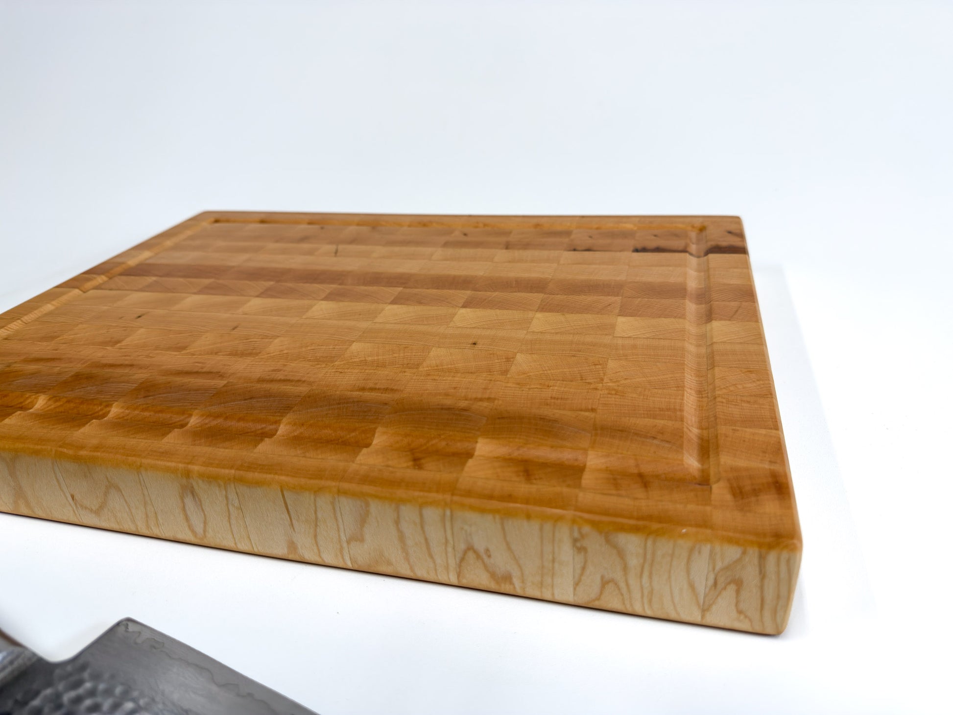 Low-angle view of the Langford maple end grain cutting board showing its thick profile and natural maple grain