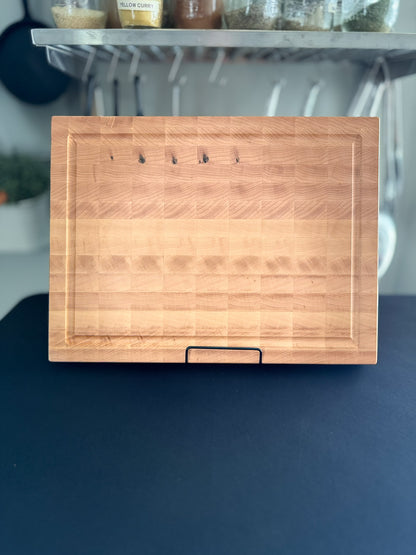 Front view of a handcrafted maple end grain cutting board highlighting its grain, surface, and edge profile.