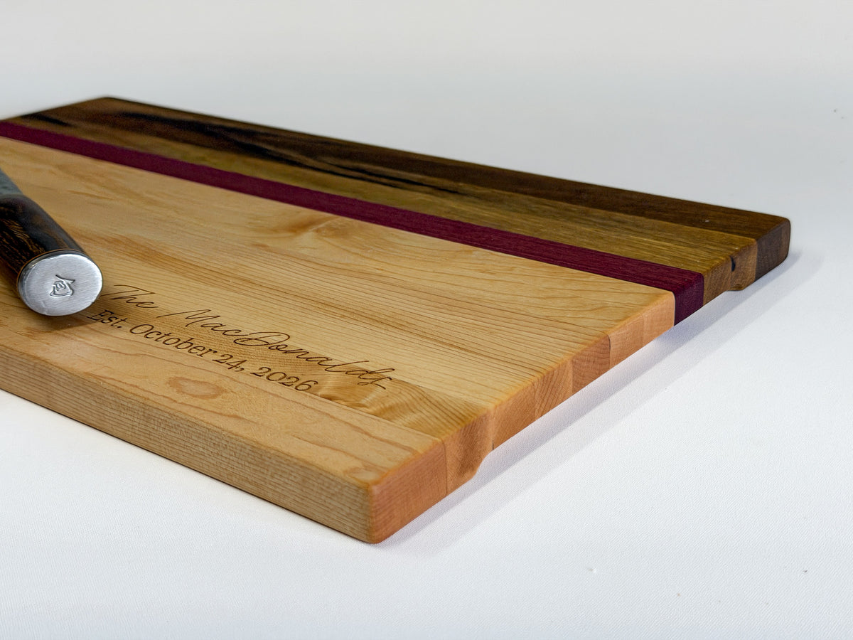 Low-angle profile of a handcrafted edge-grain charcuterie board made with maple, purpleheart and black limba.