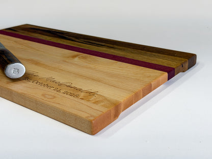 Low-angle profile of a handcrafted edge-grain charcuterie board made with maple, purpleheart and black limba.