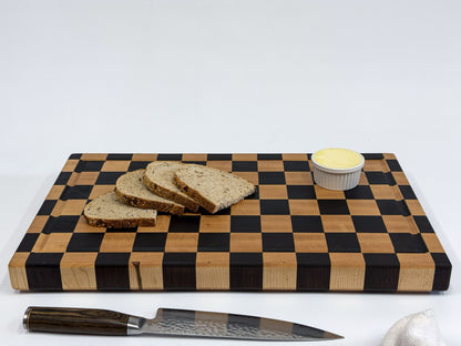 Large maple checkerboard cutting board styled with sliced bread, butter and a chef’s knife.