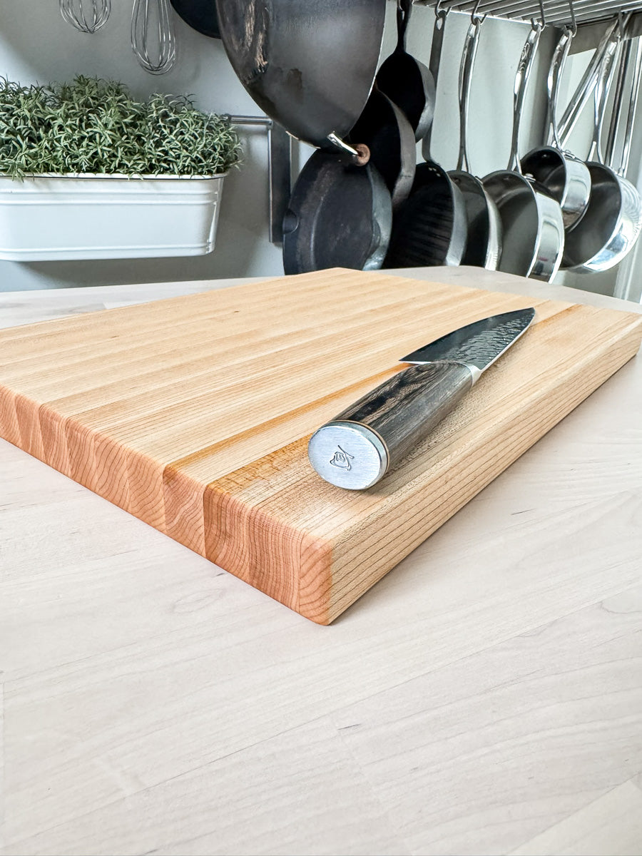 Maple edge grain cutting board with a chef's knife highlighting the hardwood grain.