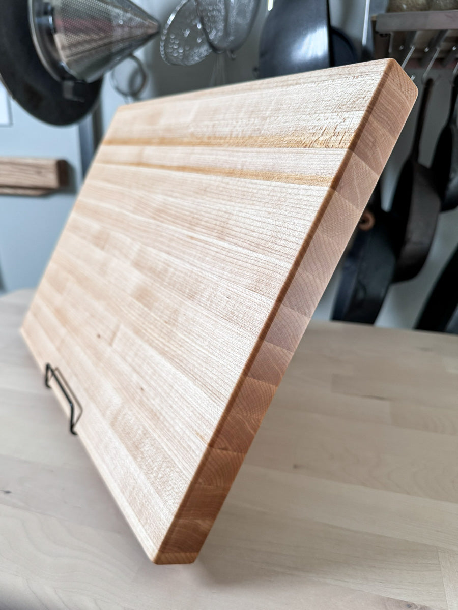 Side view of a handcrafted maple edge grain cutting board highlighting its thickness.