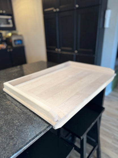 maple pierogo knead board sitting flush on  the counter with the bottom lip against the counter.
