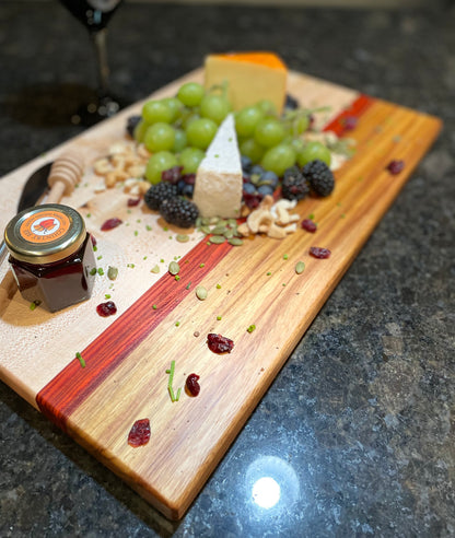 Maple, red zebrawood and canarywood edge grain charcuterie board styled with artisan cheese, grapes, berries, nuts and preserves.