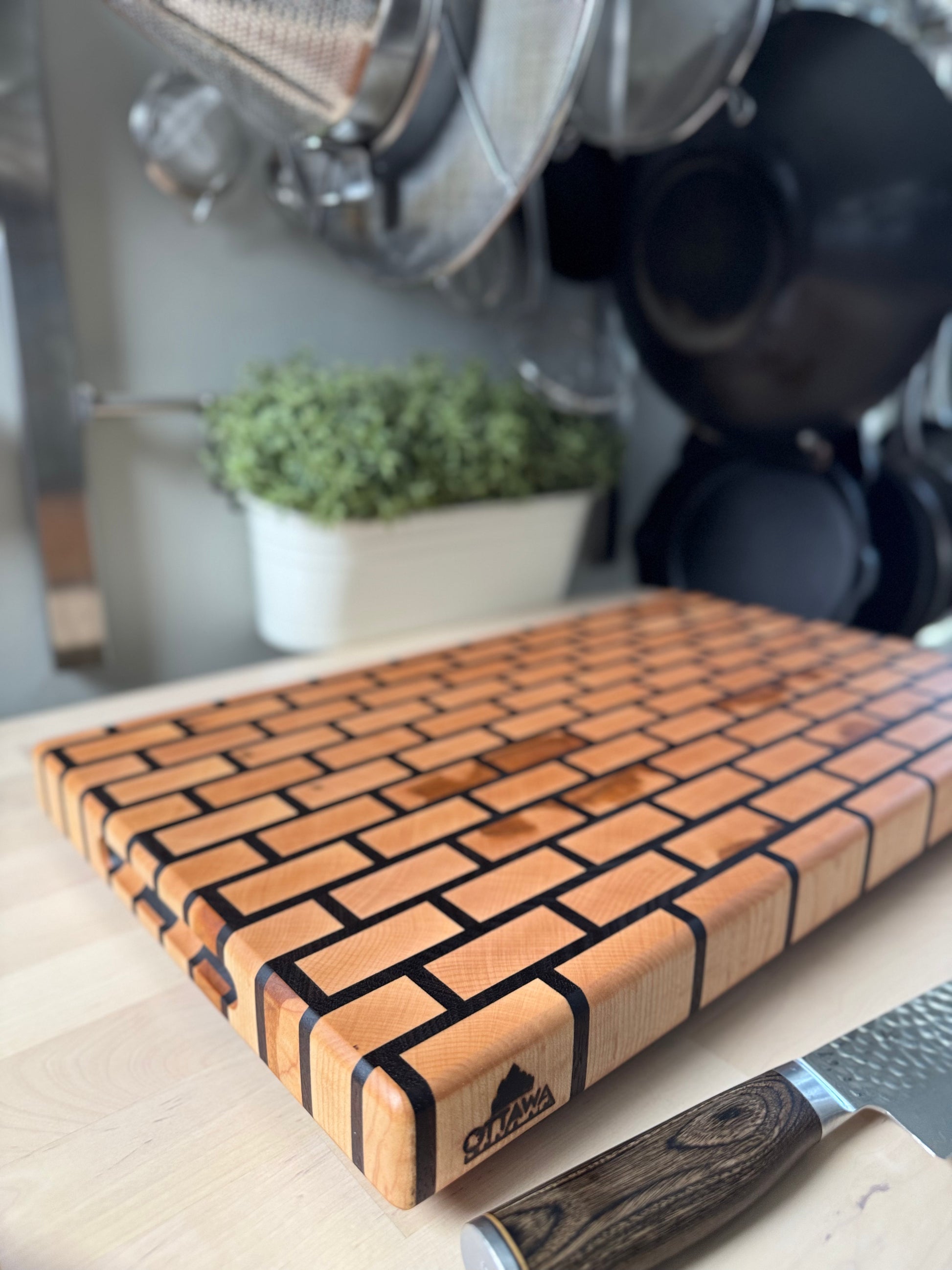 Angled view of a handcrafted maple and walnut end grain brick pattern cutting board.