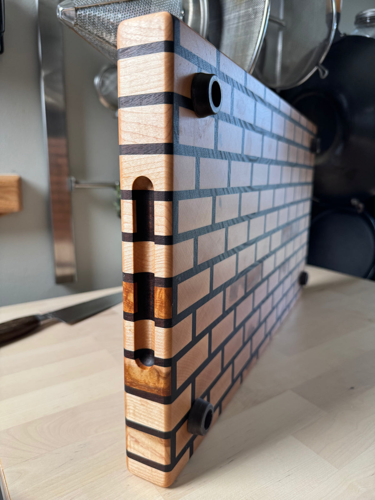 Edge detail of a handcrafted maple and walnut end grain brick pattern cutting board.