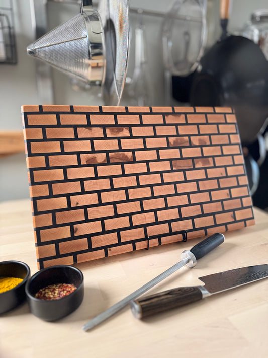 Handcrafted maple and walnut end grain brick pattern cutting board displayed standing.
