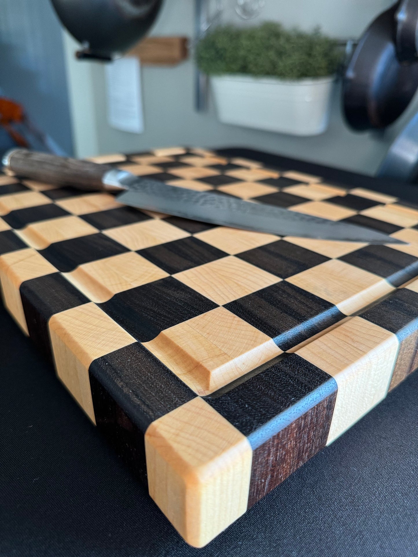 Close-up of the juice groove on a handcrafted maple and walnut end grain checkerboard cutting board.