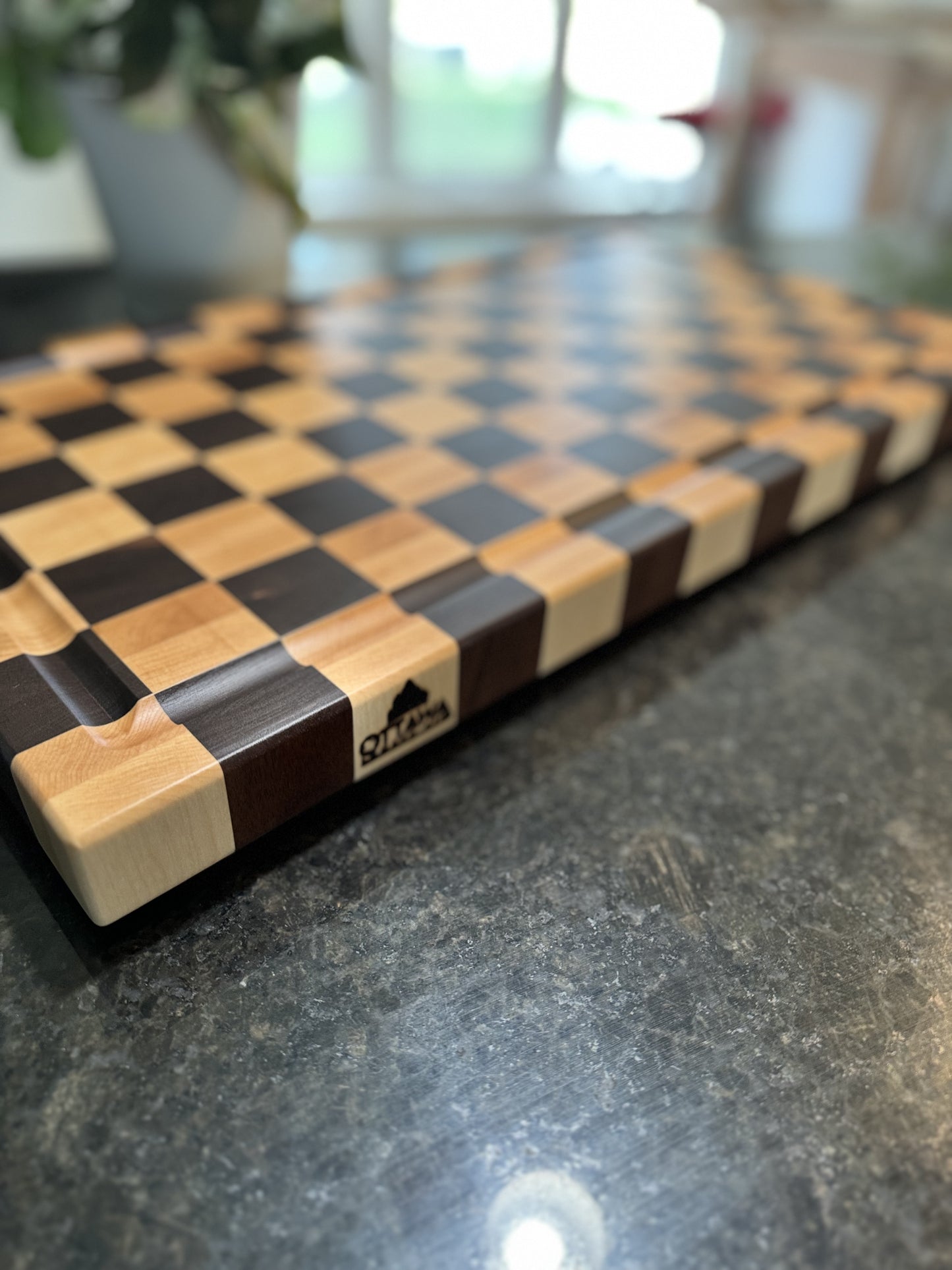 Close-up of the edge and maker's mark on a handcrafted maple and walnut end grain checkerboard cutting board.