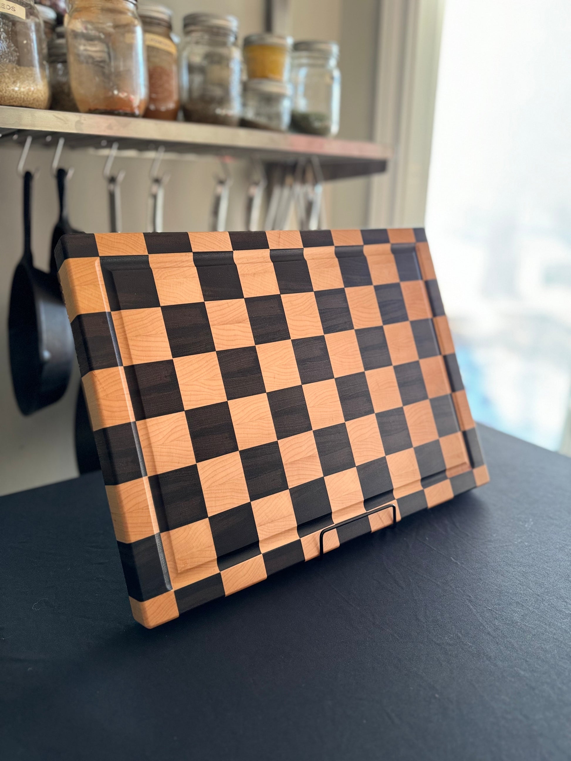 Handcrafted maple and walnut end grain checkerboard cutting board displayed standing.