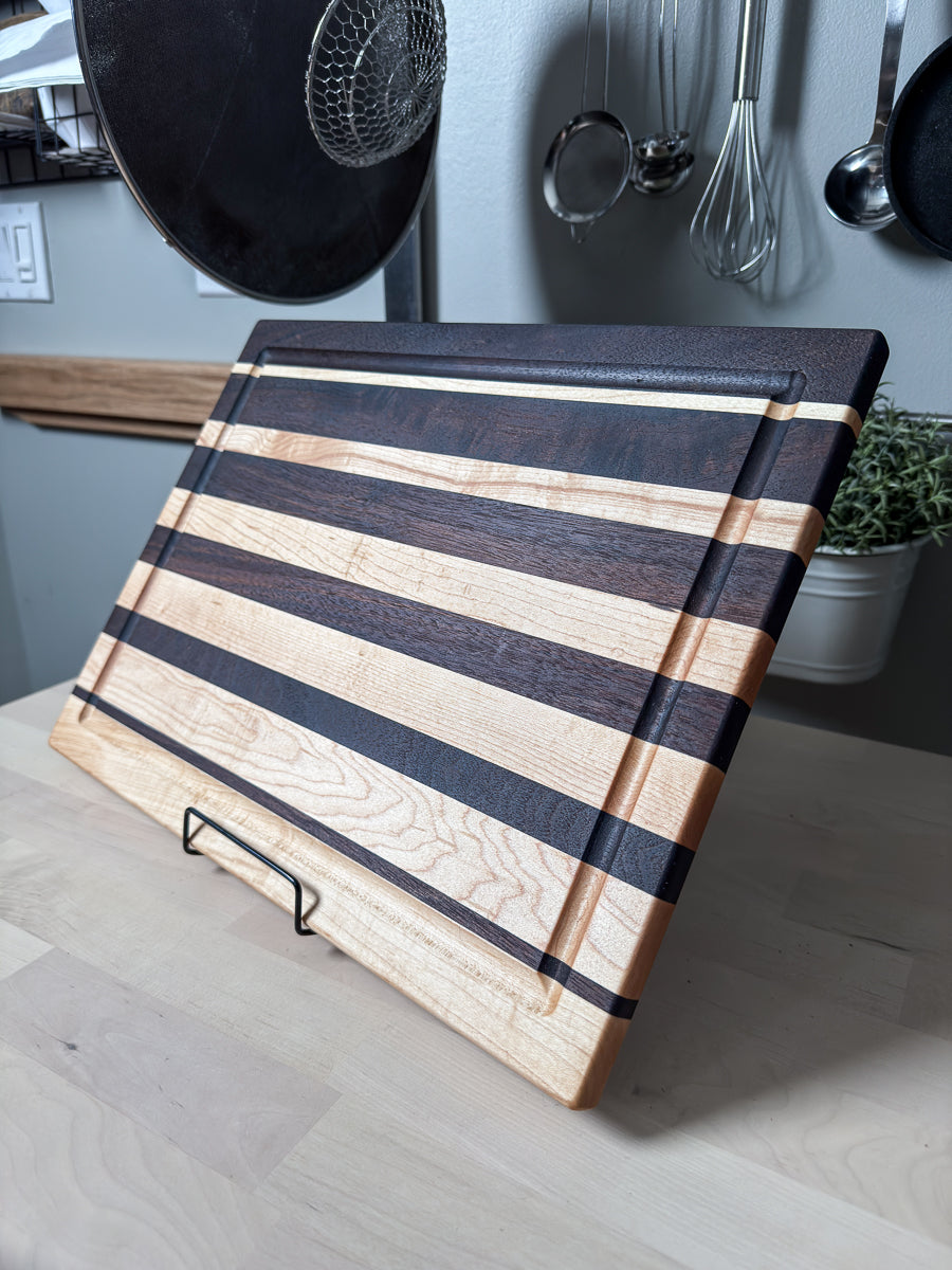 Close-up of a handcrafted maple and walnut striped cutting board highlighting the edge grain and juice groove.