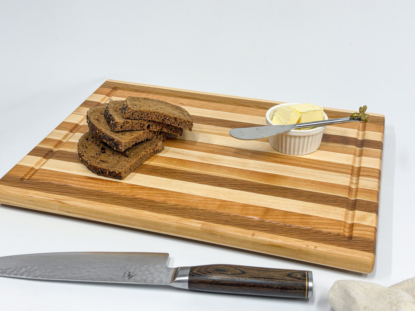 Maple, white oak and cherry edge grain cutting board styled with bread and butter for serving