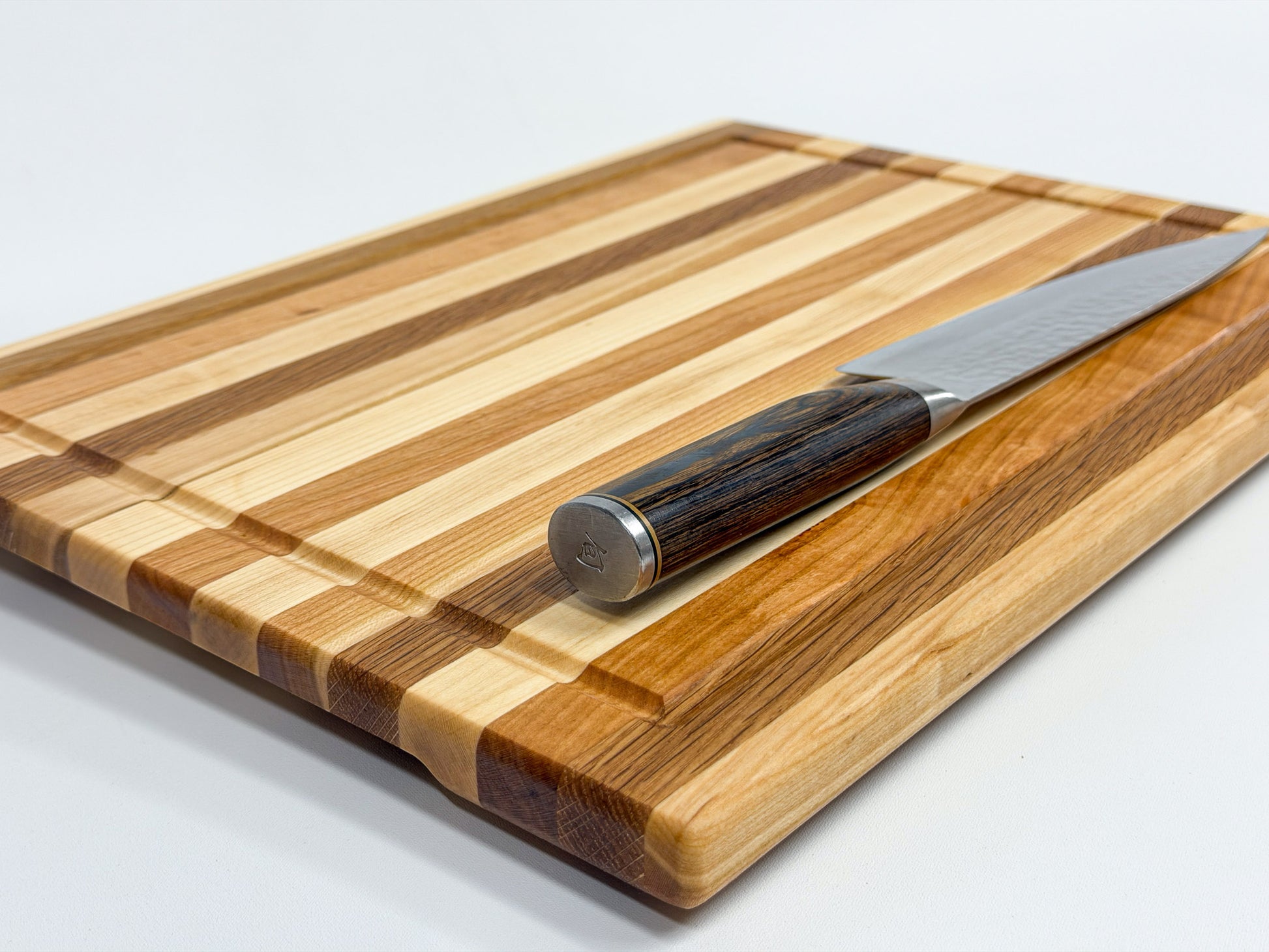 Close-up view of a maple, white oak and cherry edge grain cutting board with alternating wood strips