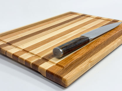 Close-up view of a maple, white oak and cherry edge grain cutting board with alternating wood strips