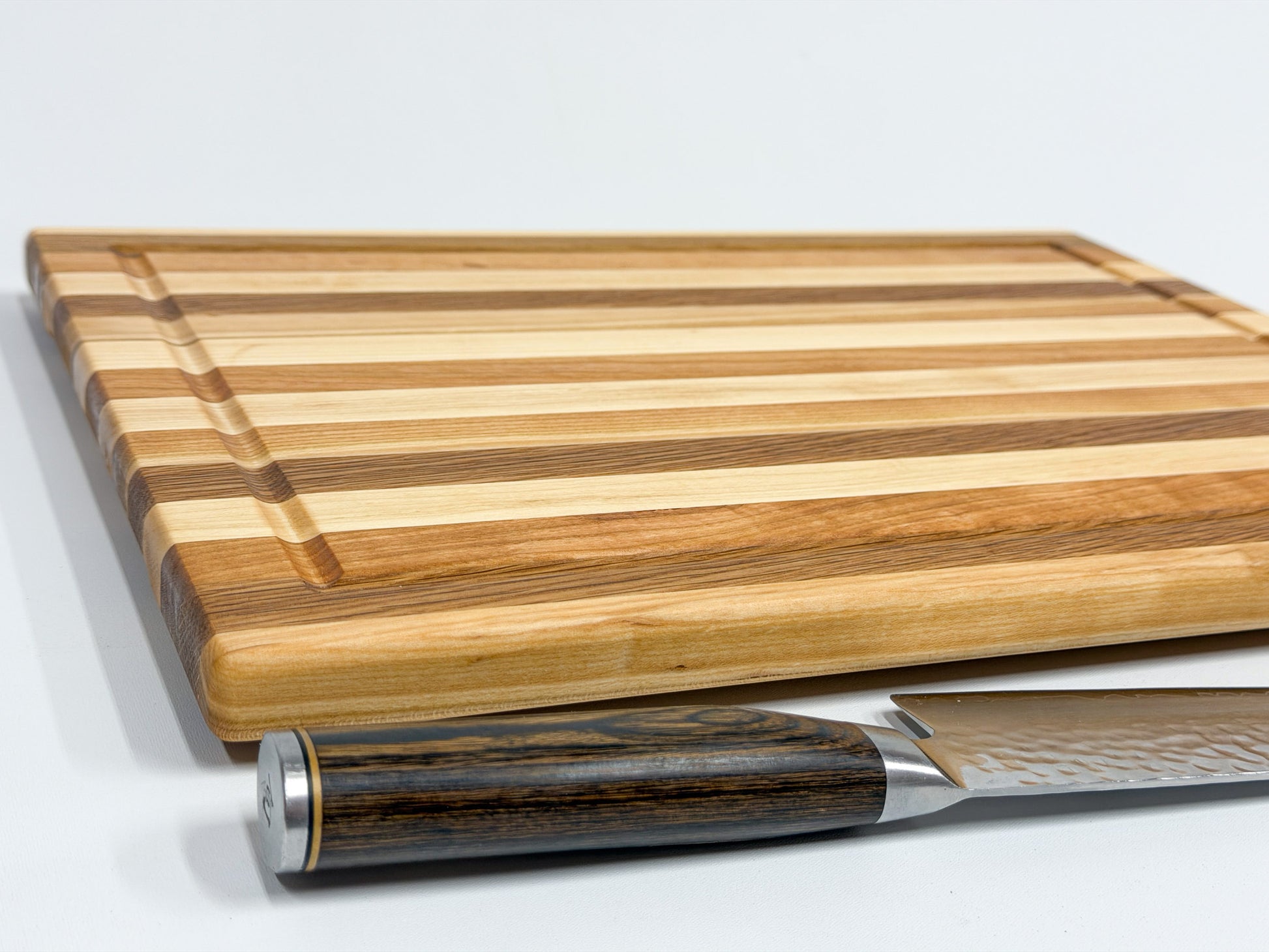 Close-up of maple, white oak and cherry edge grain cutting board showing the hardwood grain and thin profile
