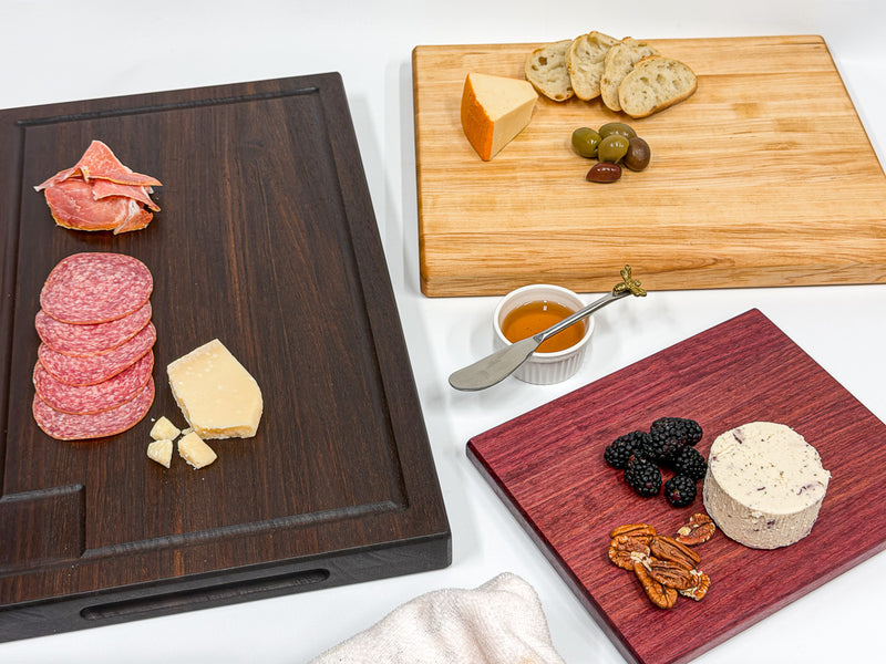 Walnut, maple and purpleheart charcuterie boards with meats, cheese, fruit and crackers.