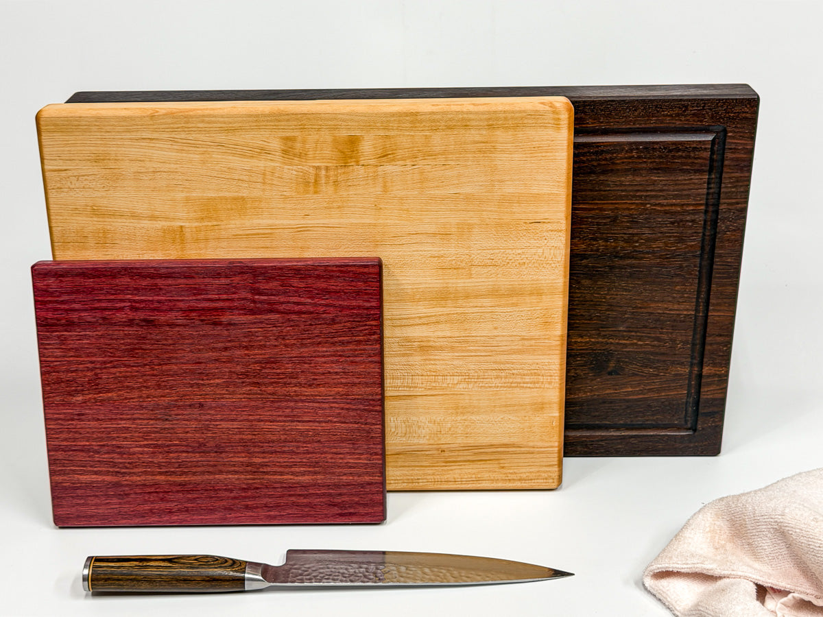 Stacked walnut, maple and purpleheart cutting boards in three sizes.