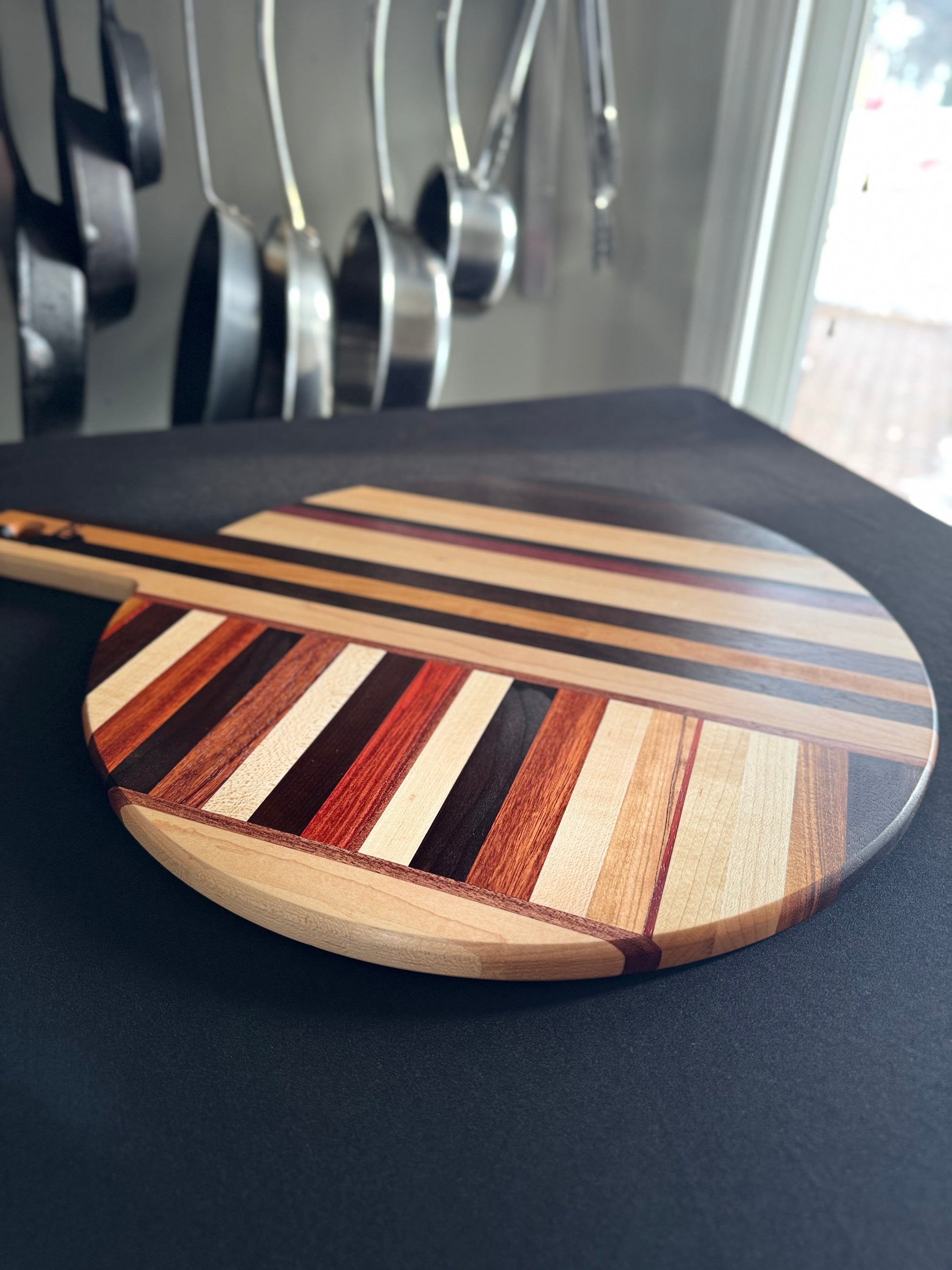 Side profile of handcrafted round pizza board showing thickness and wood grain