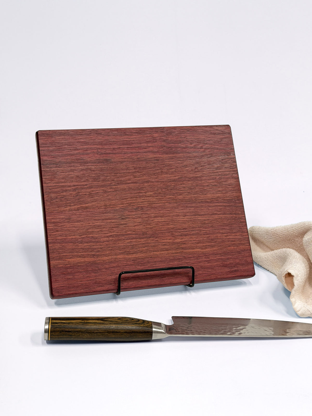 Purpleheart cutting board displayed on a stand with a chef’s knife.