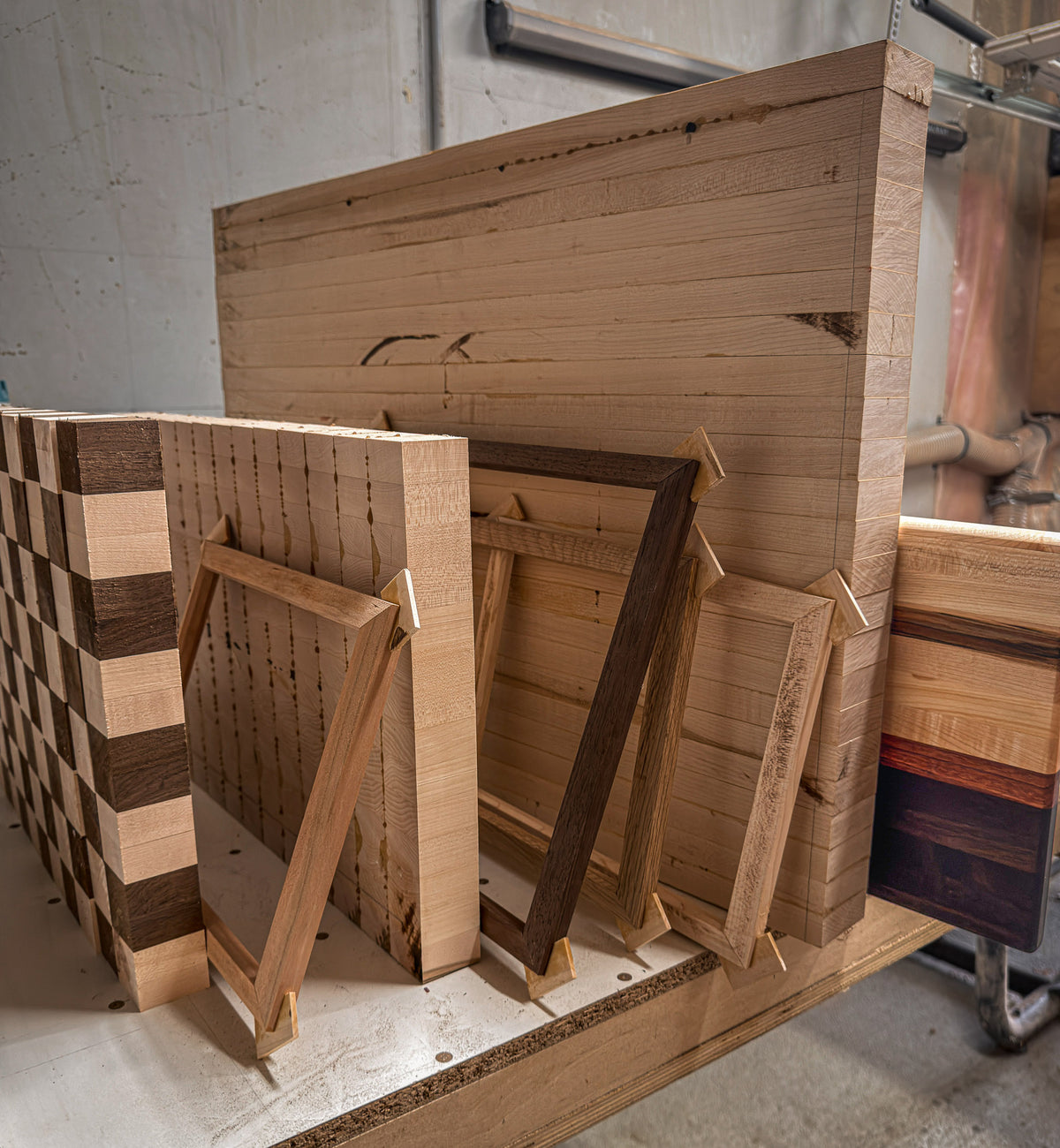 Several unfinished hardwood cutting boards and picture frames waiting between production stages in the workshop.