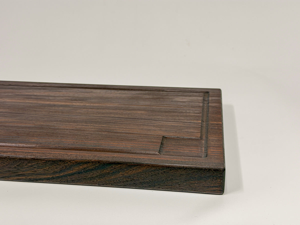 Close-up of a walnut edge-grain BBQ cutting board with routed drip groove and thick profile.