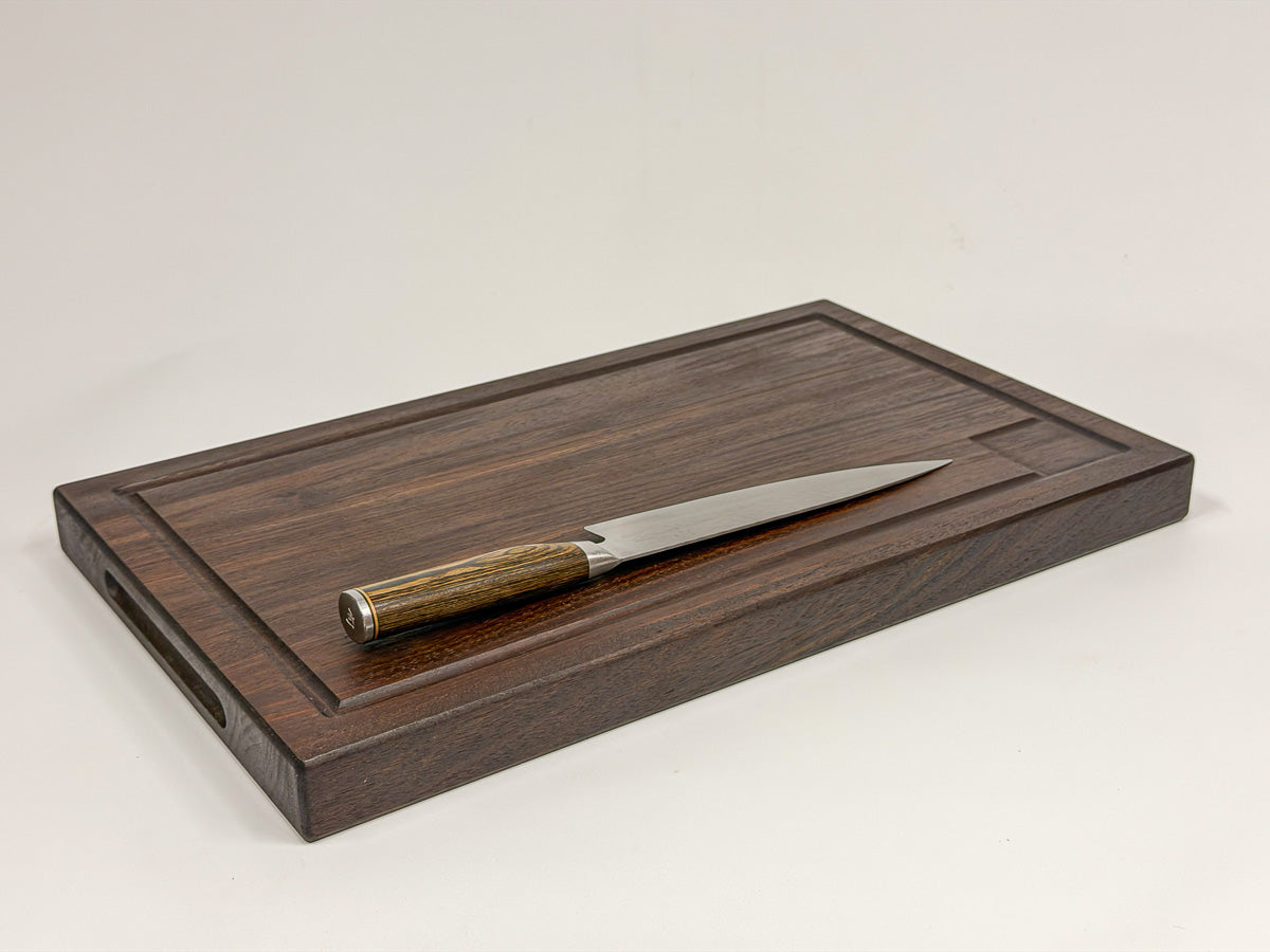 Walnut edge-grain BBQ cutting board displayed flat with a wood-handled knife.