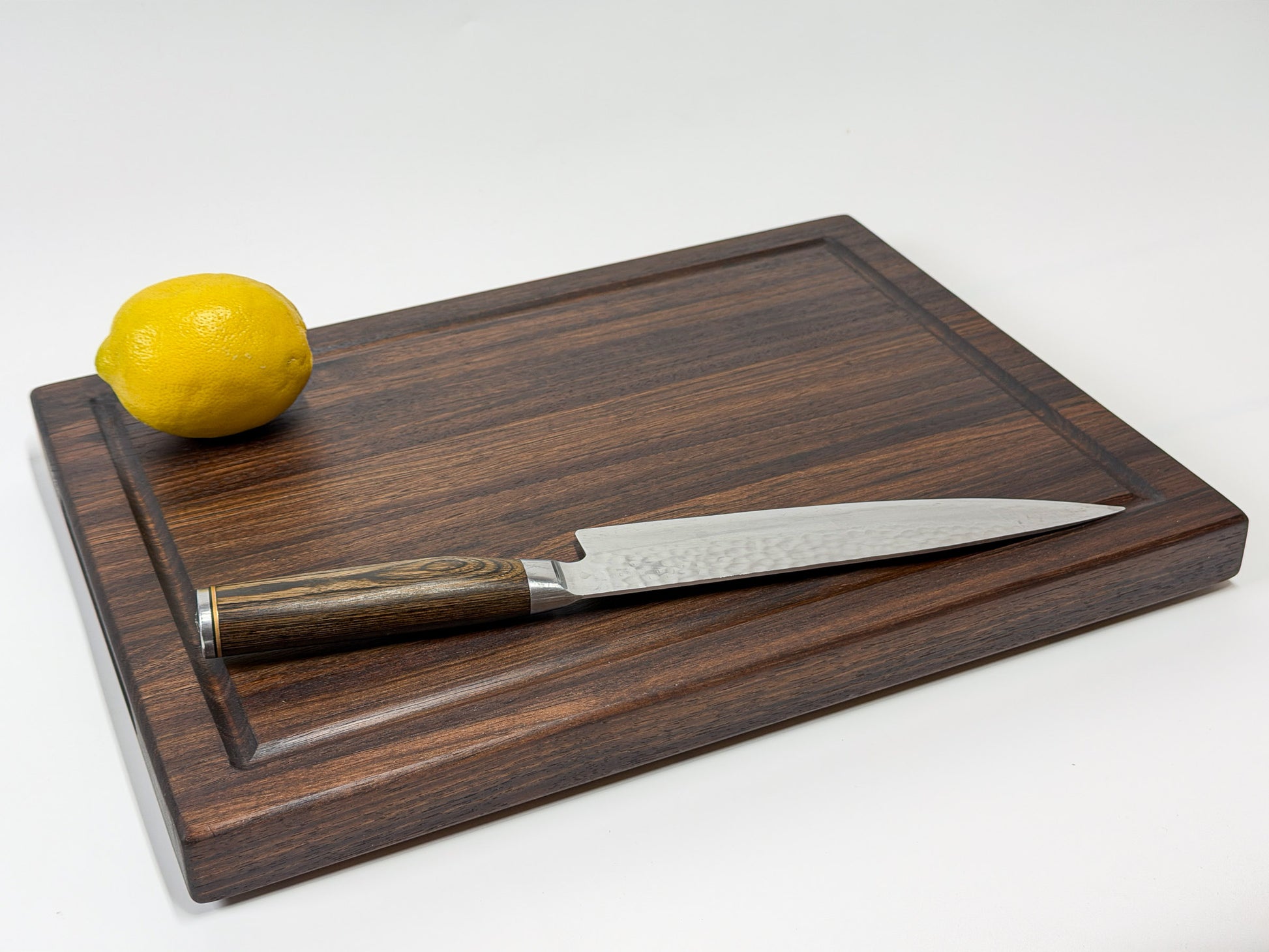 Walnut edge grain cutting board angled view with knife and lemon, handmade in Ottawa
