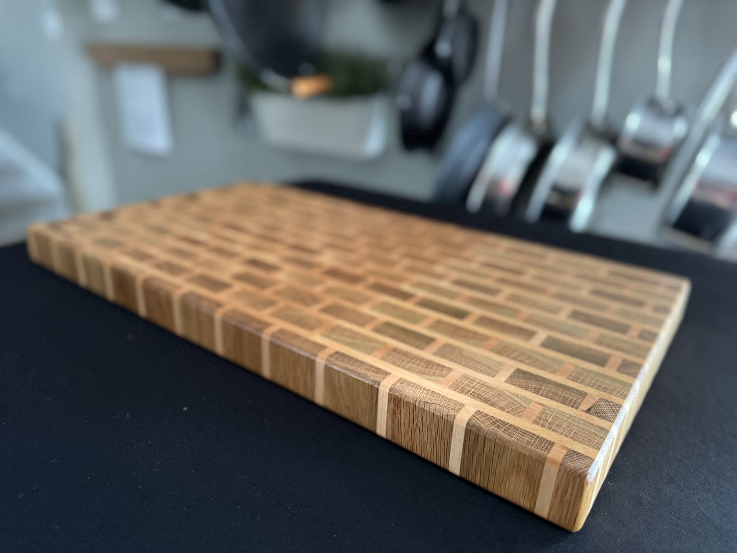 Profile view of a handcrafted white oak and cherry end grain brick pattern cutting board.