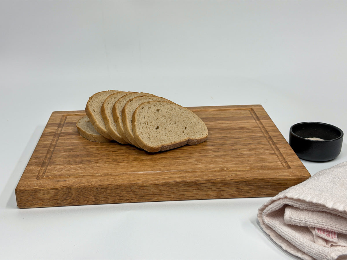 White oak cutting board styled with sliced bread, salt cellar and tea towel.