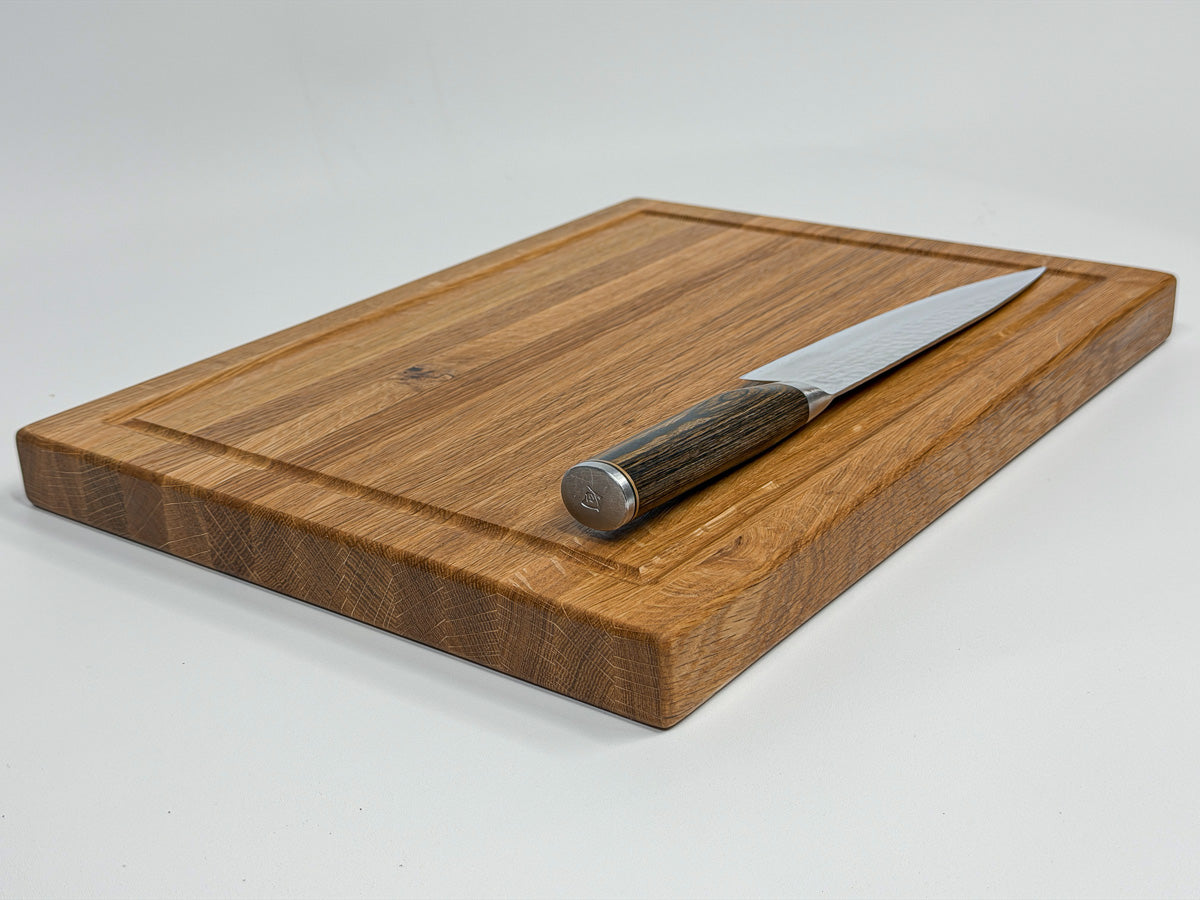 White oak cutting board displayed with a chef's knife.