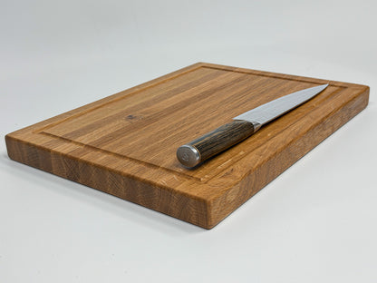 White oak cutting board displayed with a chef's knife.