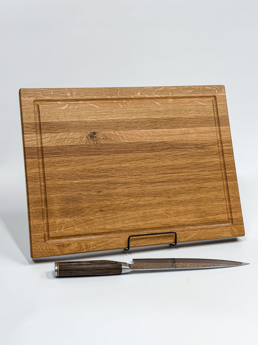 Portrait view of a handcrafted white oak cutting board with chef's knife.