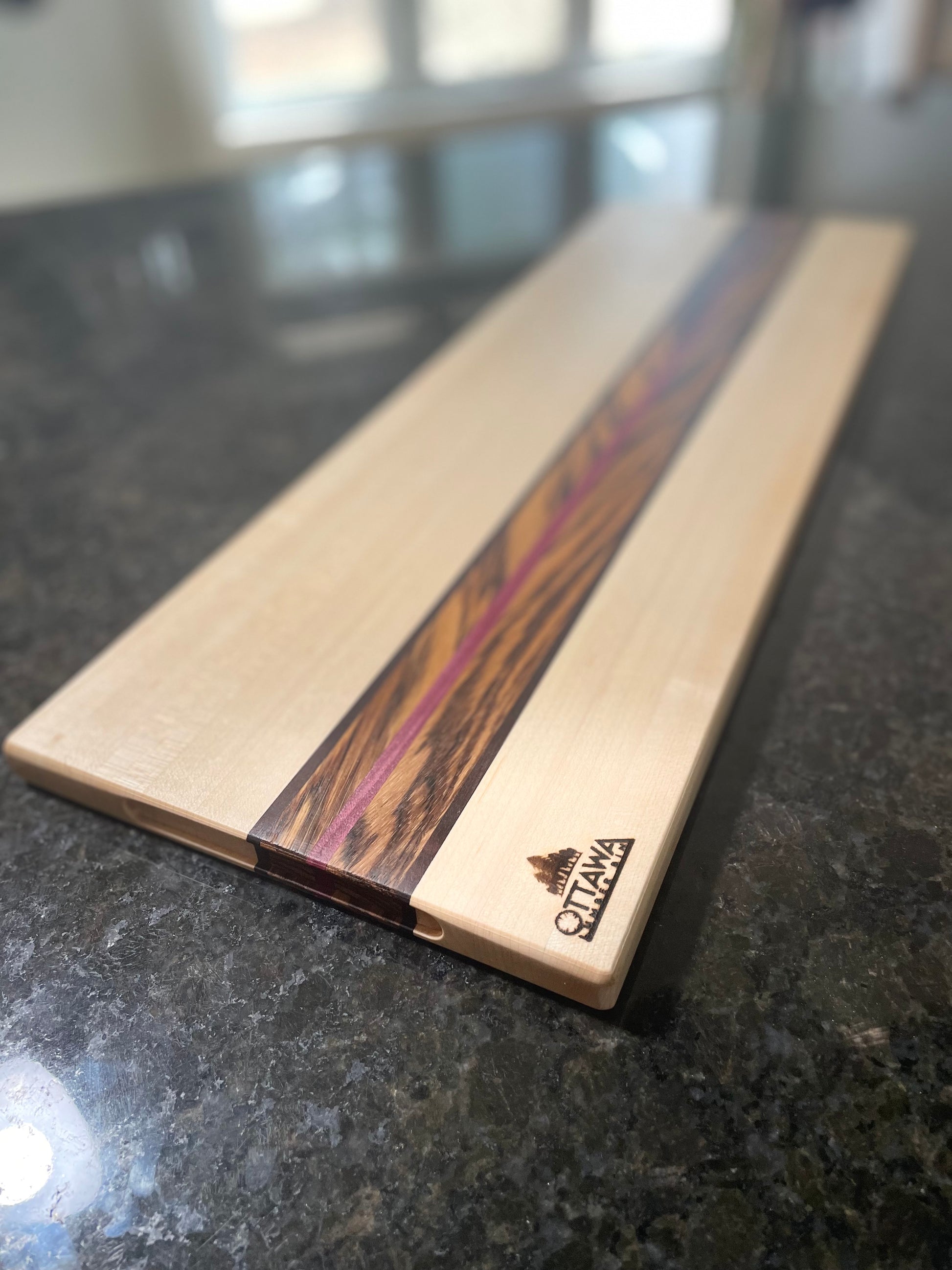 Detail view of the Zephyr handcrafted charcuterie board featuring maple, zebrawood, walnut and Purpleheart.