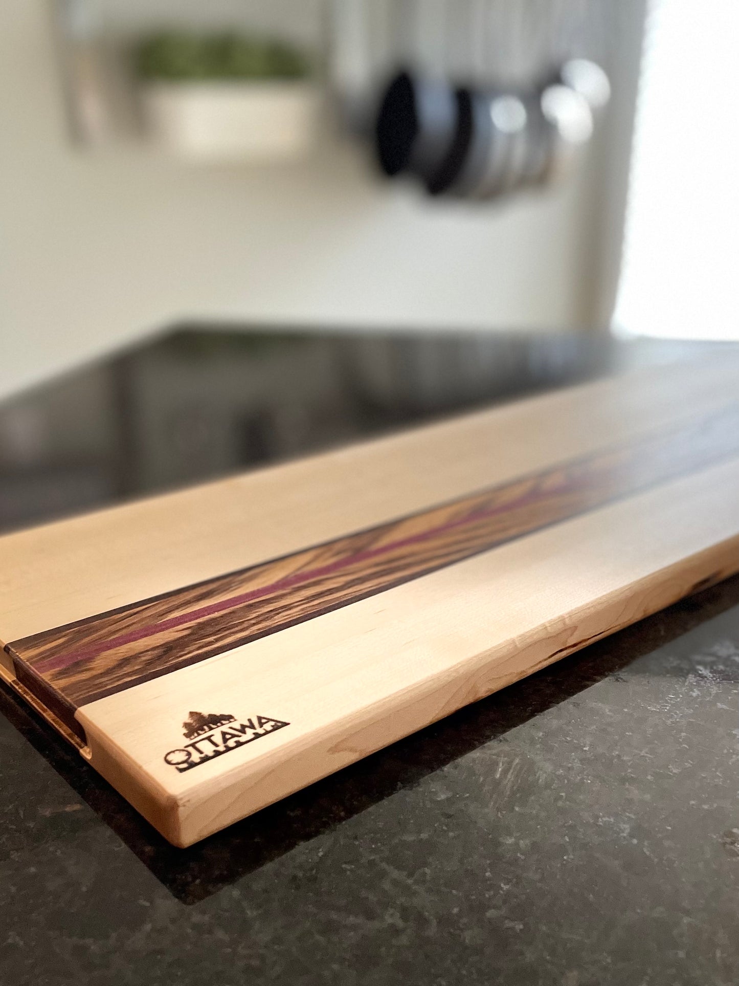 Side profile of the Zephyr charcuterie board highlighting the maple, zebrawood, walnut and Purpleheart construction.